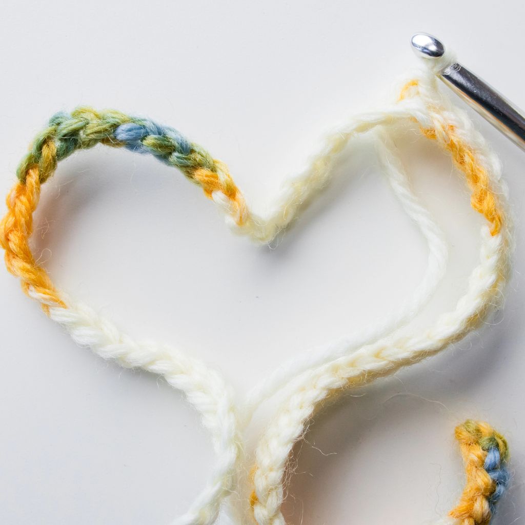 A crochet hook and a chain of stitches in the form of a heart